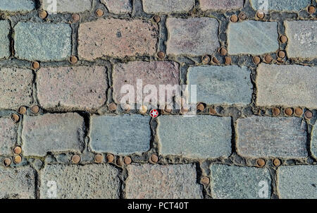 Cobblestone pavement at Admiral Bridge, Kreuzberg, Berlin, Germany, geometric urban texture with beer bottle caps Stock Photo
