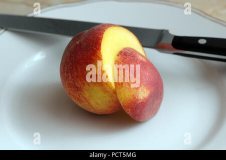 Sliced peach and knife on the white plate photo Stock Photo