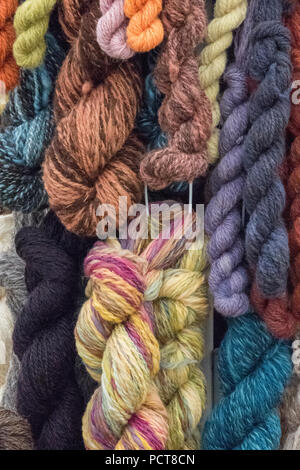 a selection of hand spun woollen hanks or skeens hanging ready for use. multi-coloured skeens and balls of natural quality wool. Stock Photo