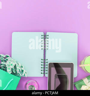 Open Notepad clean pages for writing a bouquet of flowers in a paper bag glass cocktail glass tube box gift mobile phone tablet on a purple background Stock Photo