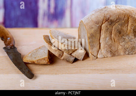 Person slicing homemade bread cutting buckwheat bread on wooden board in kitchen Stock Photo