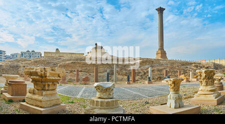 The great Pompey's Pillar with sphinx statue in front of it and ruins of ancient Serapeum Temple on territory of Amoud Al Sawari archaeological site,  Stock Photo