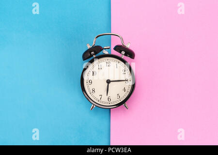 Vintage alarm clock on pink and blue background Stock Photo