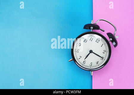 Vintage alarm clock on pink and blue background Stock Photo