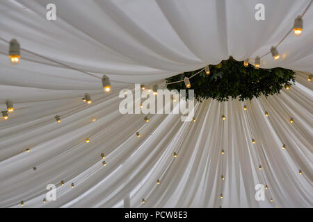 Decorated tent with bulb garland. Wedding setup white paper lanterns inside of building, under wooden roof decoration Stock Photo