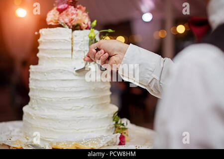 bride and a groom is cutting their wedding cake. beautiful cake. nicel light. wedding concept Stock Photo