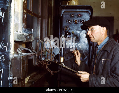 Hump master in a Chicago and Northwestern [i.e. North Western] railroad yard operating a signal switch system which extends the length of the hump track. He is thus able to control movements of locomotives pushing the train over the hump from his post at the hump office; Chicago, Ill. December 1942 Stock Photo