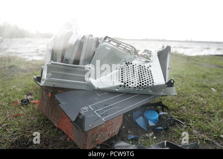 Man breaks a hammer system unit computer. Man with a sledge hammer and destroys computer in slow motion, river and forest background. Concept of confrontation between nature and technological progress. Stock Photo