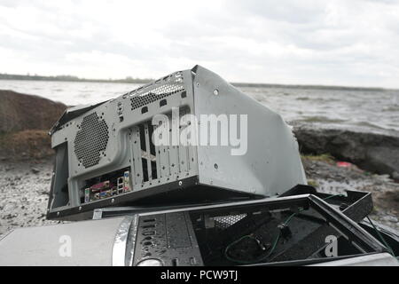 Man breaks a hammer system unit computer. Man with a sledge hammer and destroys computer in slow motion, river and forest background. Concept of confrontation between nature and technological progress. Stock Photo