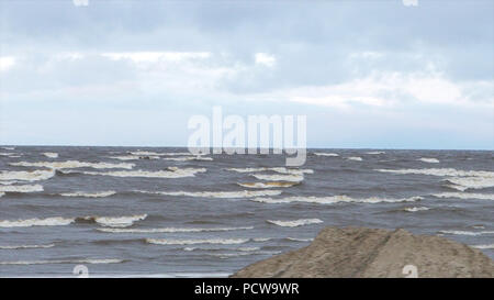 Foamy waves during a storm. Rainy day. Video. Storm on the sea. The waves are rolling on a pebble stone beach. Slow Motion. Sea water. wave. a storm warning. Stock Photo