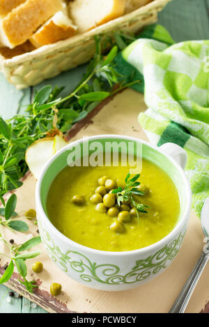 Diet menu. Puree soup with green pea in a bowl on a kitchen wooden table. The concept of healthy eating. Stock Photo