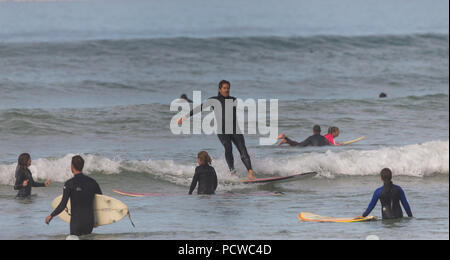 man or surfer in wetsuit standing on surfboard overbalancing or losing his balance as he arrives onshore at Muizenberg, False Bay, Cape Peninsula Stock Photo