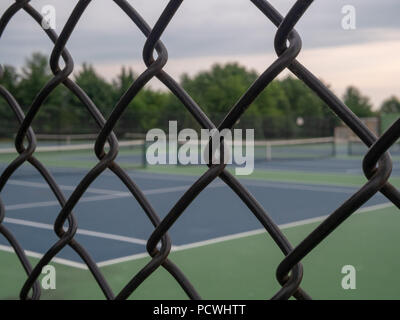 Tennis courts in background with black fence framing in foreground Stock Photo
