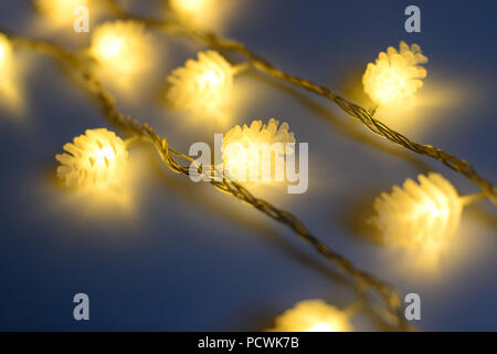 Blurred yellow christmas lights in shape of cones in three rows on dark background , low depth of focus. Stock Photo