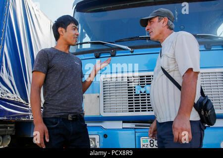 (180804) -- HORGOS, Aug. 4, 2018 (Xinhua) -- A driver from Kazakhstan (R) communicates with a Chinese translator in Horgos, northwest China's Xinjiang Uygur Autonomous Region, Aug. 4, 2018. The trade at the China-Kazakhstan Horgos International Border Cooperation Center enters a busy season since the beginning of the summer tourism peak. (Xinhua/Huang Zhen)(gxn) Stock Photo