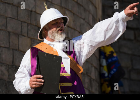 Windsor, UK. 4th August, 2018. Chris Brown, Official Town Crier of the Royal Borough of Windsor and Maidenhead, introduces town criers taking part in the Ancient and Honourable Guild of Town Criers (AHGTC) National Championship beneath the walls of Windsor Castle. Forty town criers from across the UK and two from Australia compete in two rounds of crying, the first a home cry scored on diction, inflection, clarity and volume and the second a cry on the topic of 'A Celebration’. Credit: Mark Kerrison/Alamy Live News Stock Photo