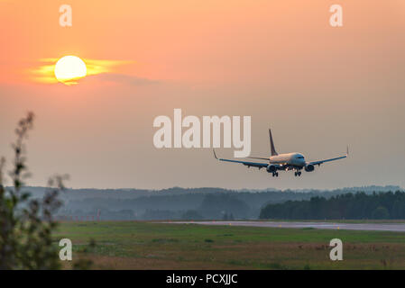 A plane approaches the airport during sunset.