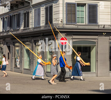 Zurich, Switzerland - August 1, 2018: people carrying alpine horns passing along a street in the old town of city of Zurich to participate in the para Stock Photo