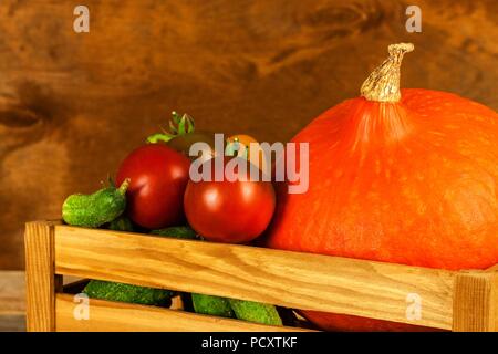 Hokkaido pumpkin in a wooden box with vegetables. Harvesting vegetables on the farm. Sales of pumpkins Stock Photo