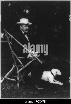 Alton Brooks Parker, 1852-1926, full length portrait, seated in rustic chair, facing right; with dog on lawn; wearing straw hat Stock Photo