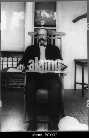 Alton Brooks Parker, 1852-1926, full length portrait, seated, facing slightly left; in classroom desk chair reading Harper's Magazine Stock Photo