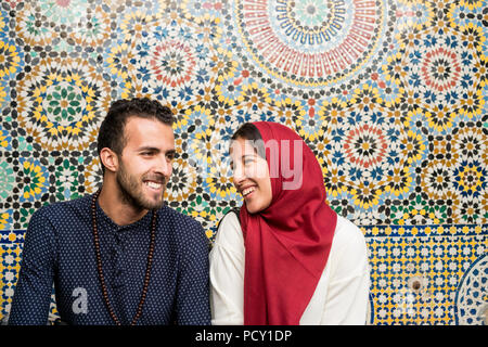 Young Muslim couple in relationship talking and smiling in front of arabesque oriental decoration Stock Photo