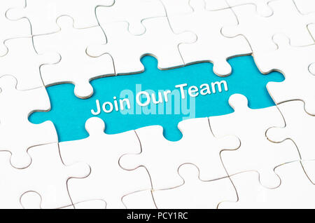 Join Our Team texts with white jigsaw puzzle board on blue background. Business concept. Stock Photo