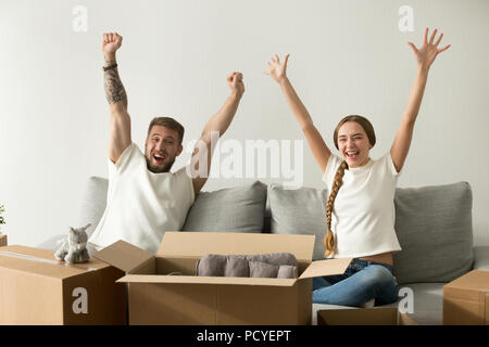 Excited couple raising hands happy to move to new house Stock Photo