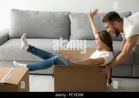 Happy couple riding in boxes having fun unpacking boxes Stock Photo