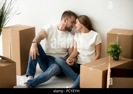 Spouses looking at each other sitting on floor while moving Stock Photo