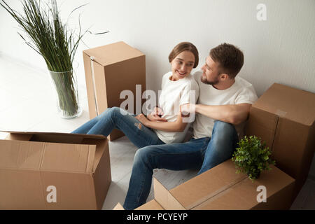 Happy couple hugging sitting on floor of own home Stock Photo