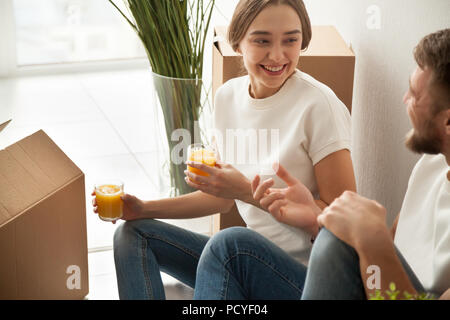 Smiling spouses drinking juice during break in unpacking boxes Stock Photo