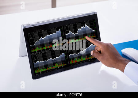 Close-up Of A Businessman Pointing On Stock Chart Over The Laptop Screen Stock Photo