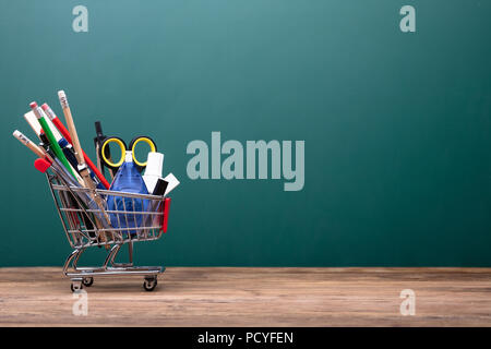 Cart With Various School Supplies On Desk In Classroom Stock Photo