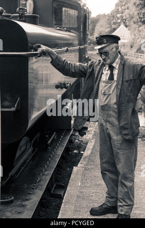 A driver looks on as his steam engine is uncoupled at Boscarne Junction Station, Cornwall, on the Bodmin and Wenford Steam Railway Stock Photo