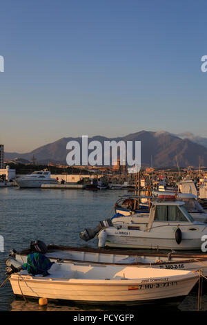 Small local fishing boats moored in the small marina of Puerto de la Duquesa on the Costa del Sol, near Estepona, with Sierra Bermeja rising behind Stock Photo