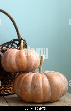 Ripe pumpkins on a wooden background and in a basket. Rustic style, selective focus. Stock Photo