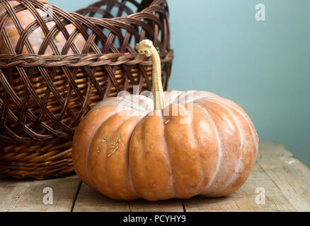 Ripe pumpkins on a wooden background and in a basket. Rustic style, selective focus. Stock Photo