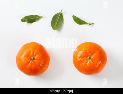 two ripe tangerines and leaves on white background Stock Photo