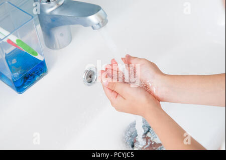 healthy white kid washing his hands under water in bathroom in morning hygiene Stock Photo