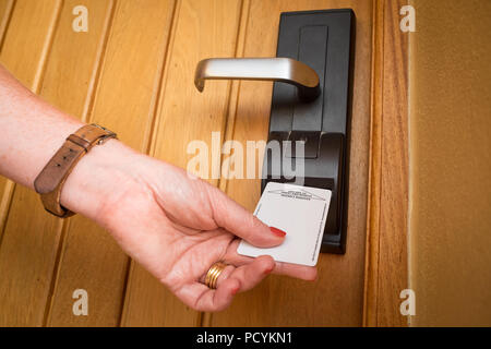 A woman entering a hotel room using an electric key card Stock Photo