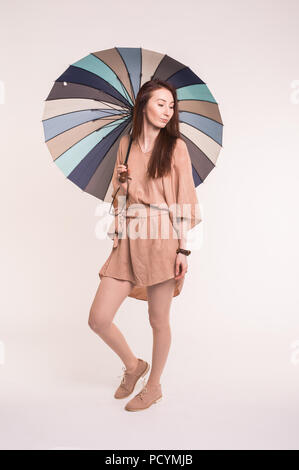 Portrait of beautiful asian brunette female standing under umbrella over white background Stock Photo