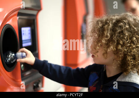 Child with curls puts bottles in vending machine Stock Photo