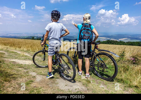 Bikers cycling on a mountain trail, Velka Javorina mountain,  Czech Slovak border in White Carpathians Mountains Czech Republic cycling countryside Stock Photo