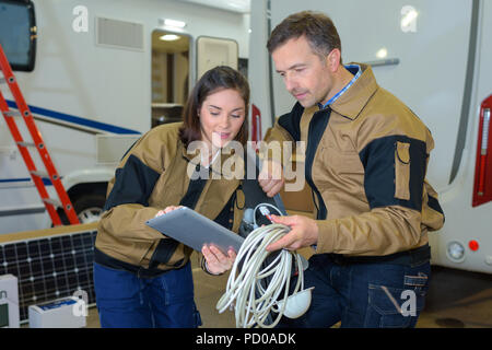 2 workers discussing near campers at camper factory Stock Photo