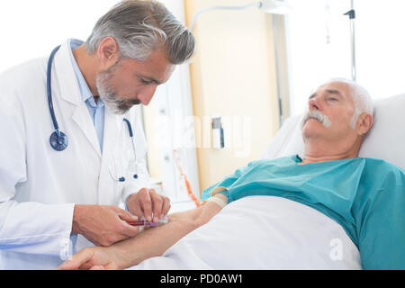 senior man undergoing blood test in clinic Stock Photo