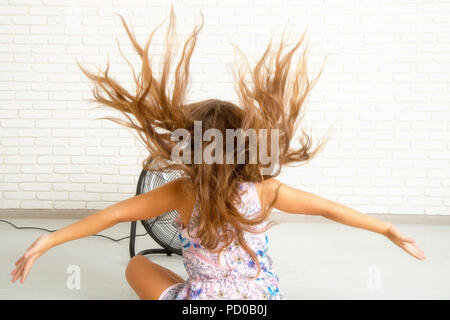 the girl is sitting in front of the fan Stock Photo