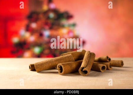 Lot of whole dry brown cinnamon stick stack with christmas tree in red background Stock Photo