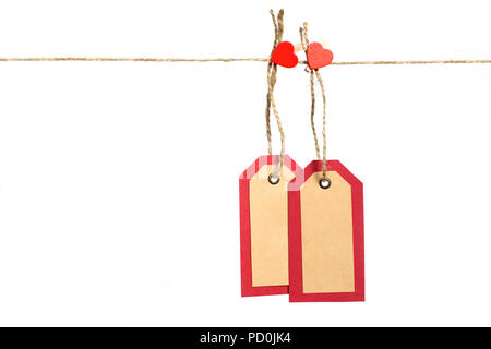 Two red and brown paper tags hanging on the rope by heart shape pin with copy space isolated on white background. St.Valentines gift concept. Stock Photo