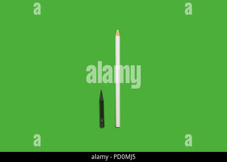 Black small used and white long new pencils lying on a green background. concept of office and educational chancery Stock Photo